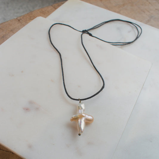 The NOIRÉE  Pearl Cross Necklace on Black Cord